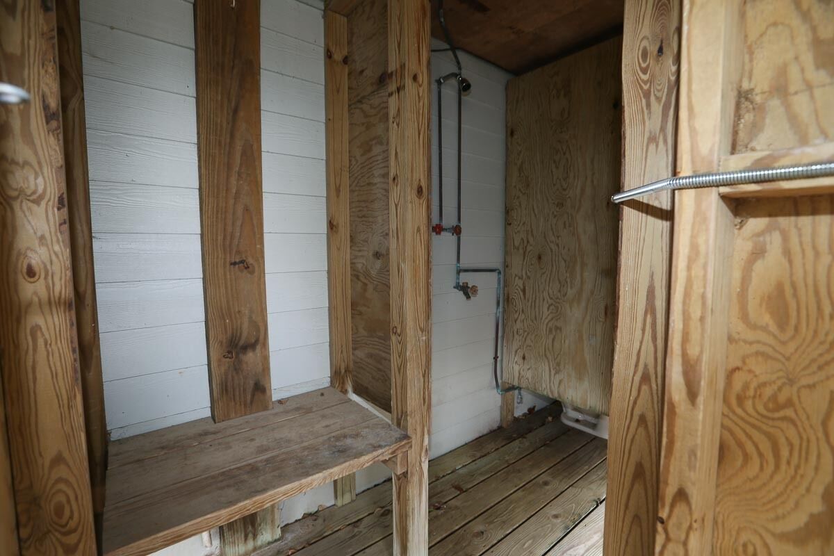 Una cabaña de madera con un banco y una barra de metal.