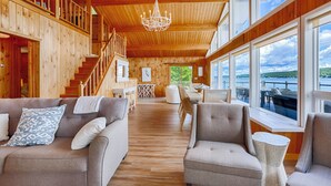 Un'ampia stanza in legno con una scala, un lampadario e vista sull'acqua.