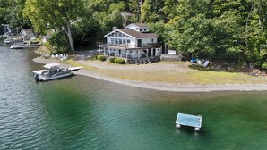 Una proprietà sul lago con una casa grande, barche ormeggiate e una piccola imbarcazione sull'acqua.