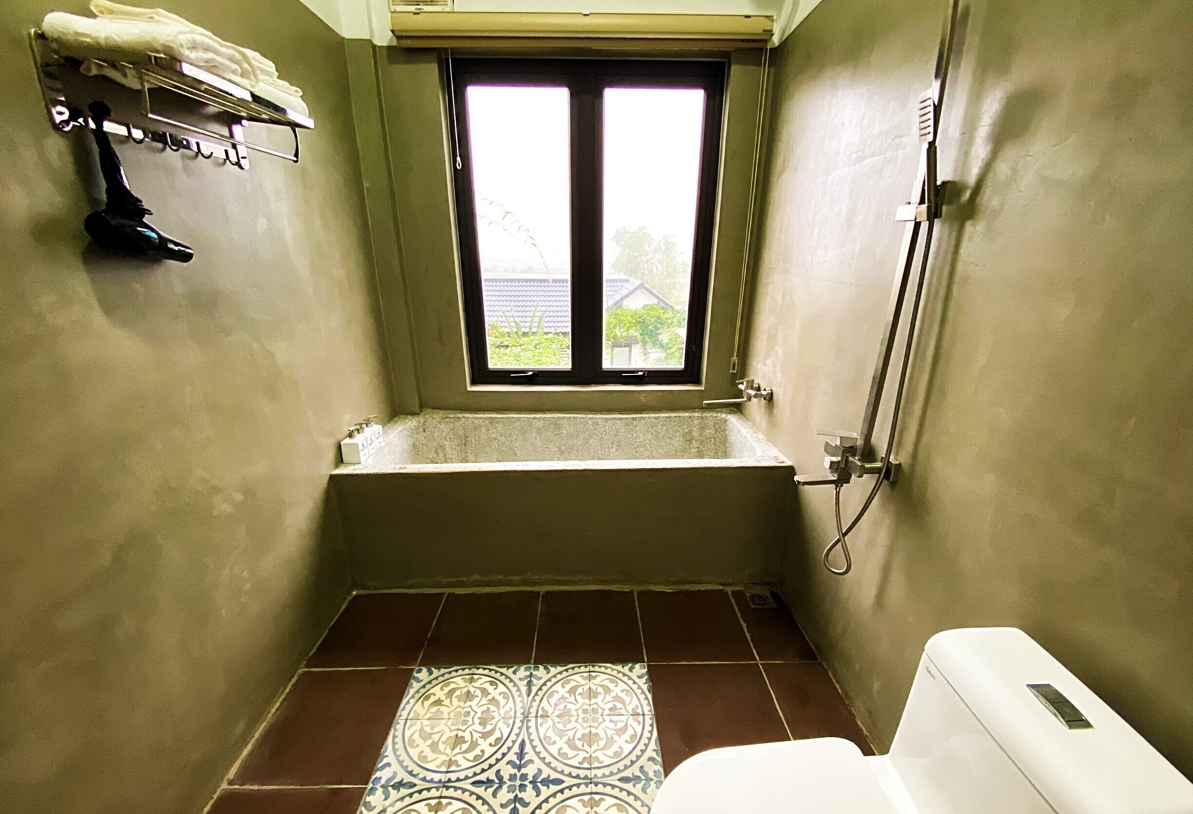 Un baño pequeño con bañera, ventana y retrete.