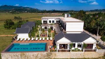 A resort with multiple villas, a swimming pool, and a view of the surrounding landscape.