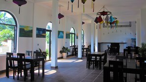 A spacious indoor area with multiple tables and chairs, large windows, and hanging decorative lanterns.