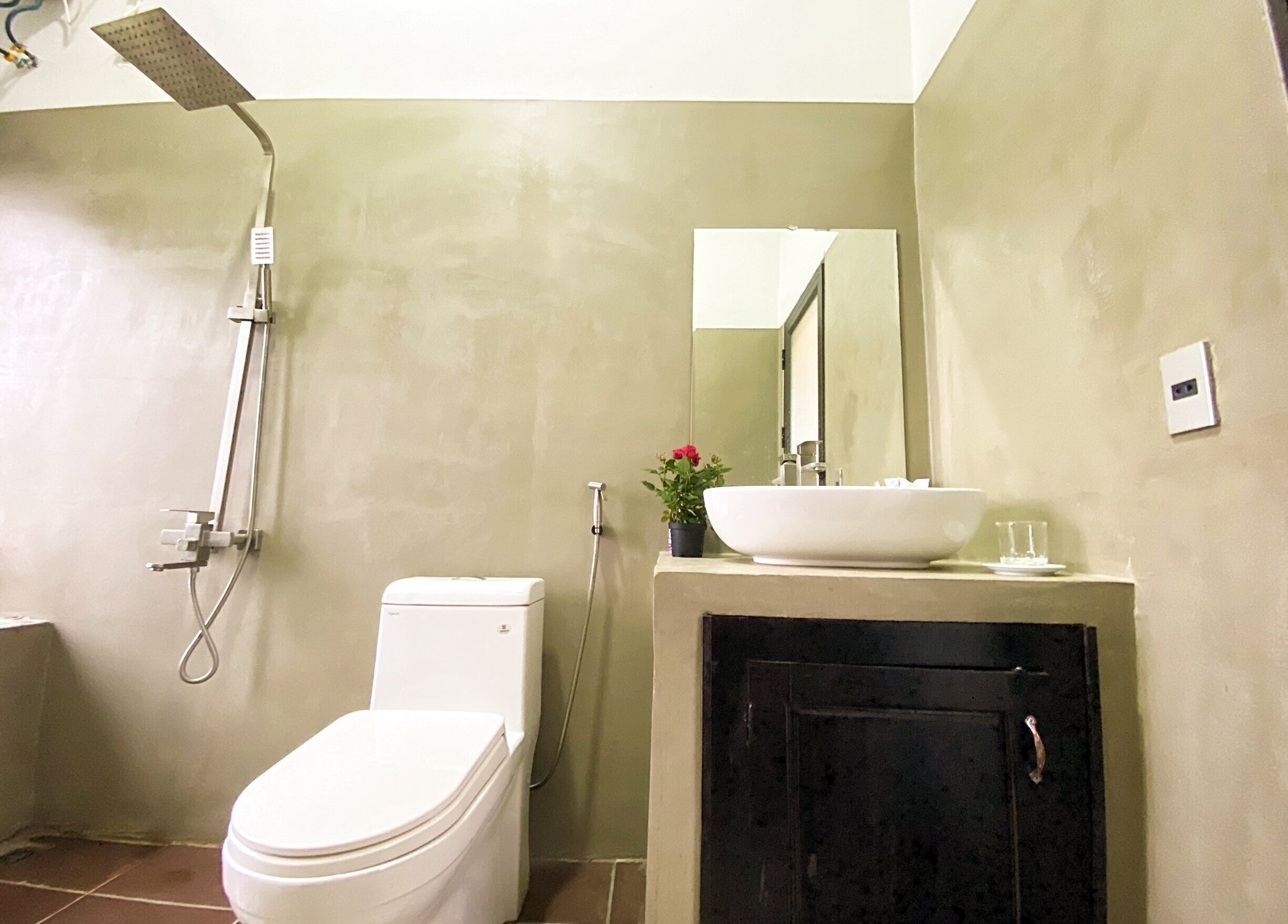 A bathroom with a toilet, a sink, a shower, and a cabinet.