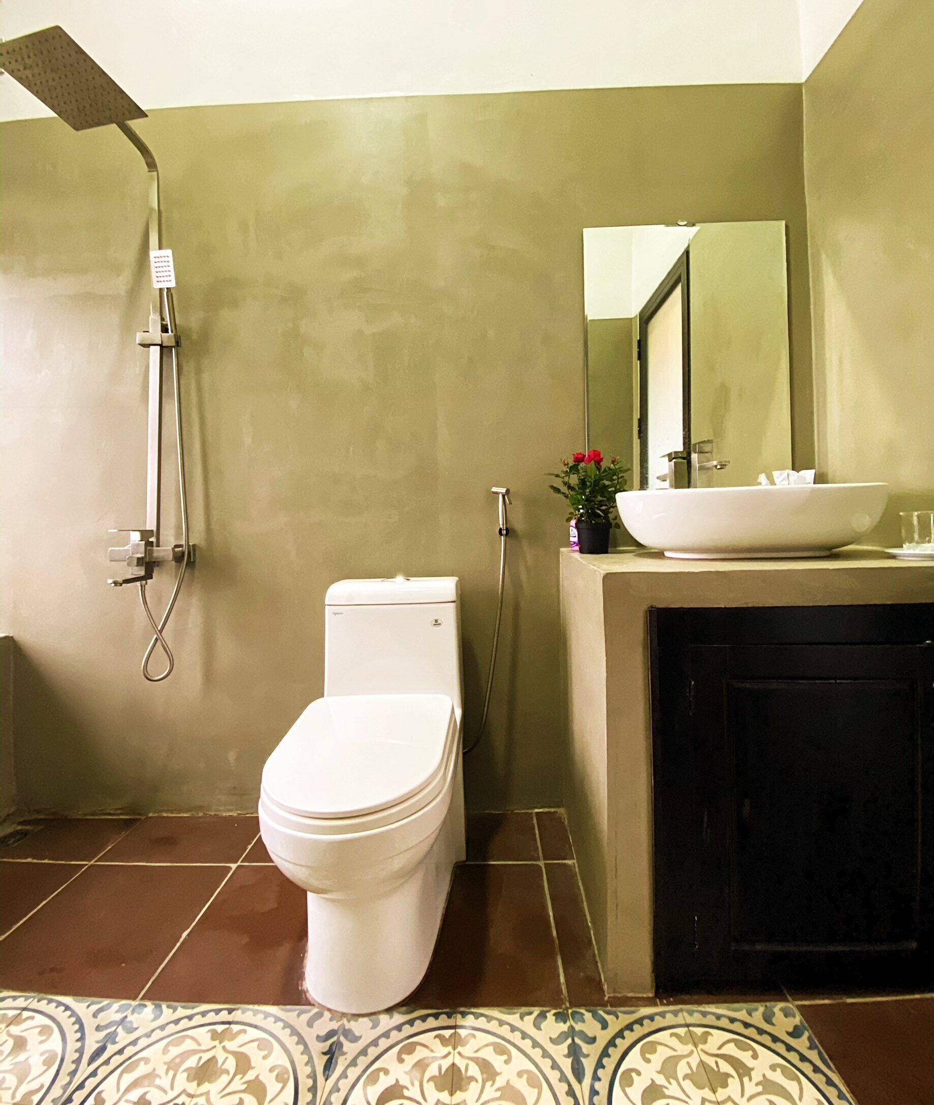 A bathroom with a toilet, a shower, a sink, and a mirror.