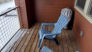A wooden deck with two blue Adirondack chairs and a white wall-mounted light fixture. - Granby Ranch Ski Condo with King Bed & Bunkbed! (Granby)