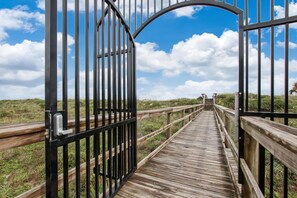 A wooden boardwalk leading to a gate with a keypad lock. - Renovated, Cozy 2Bd 2Ba, Steps from Private Beach & Pool! (St. Augustine)