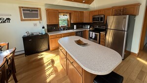 A modern kitchen with wooden cabinets, stainless steel appliances, and a granite countertop. - Peaceful Catskill Mountains Cabin (Lexington)