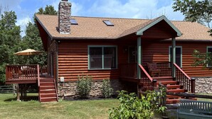 A log cabin with a stone chimney, a porch with steps, and a small garden. - Peaceful Catskill Mountains Cabin (Lexington)