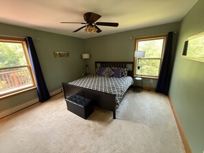 Ein Schlafzimmer mit einem Bett, einem Deckenventilator, einem Fenster, einer Stehlampe und einem kleinen Tisch.