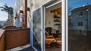 Edifici modern amb una porta corredissa de vidre que dona a una zona d'estar exterior amb mobles de fusta.