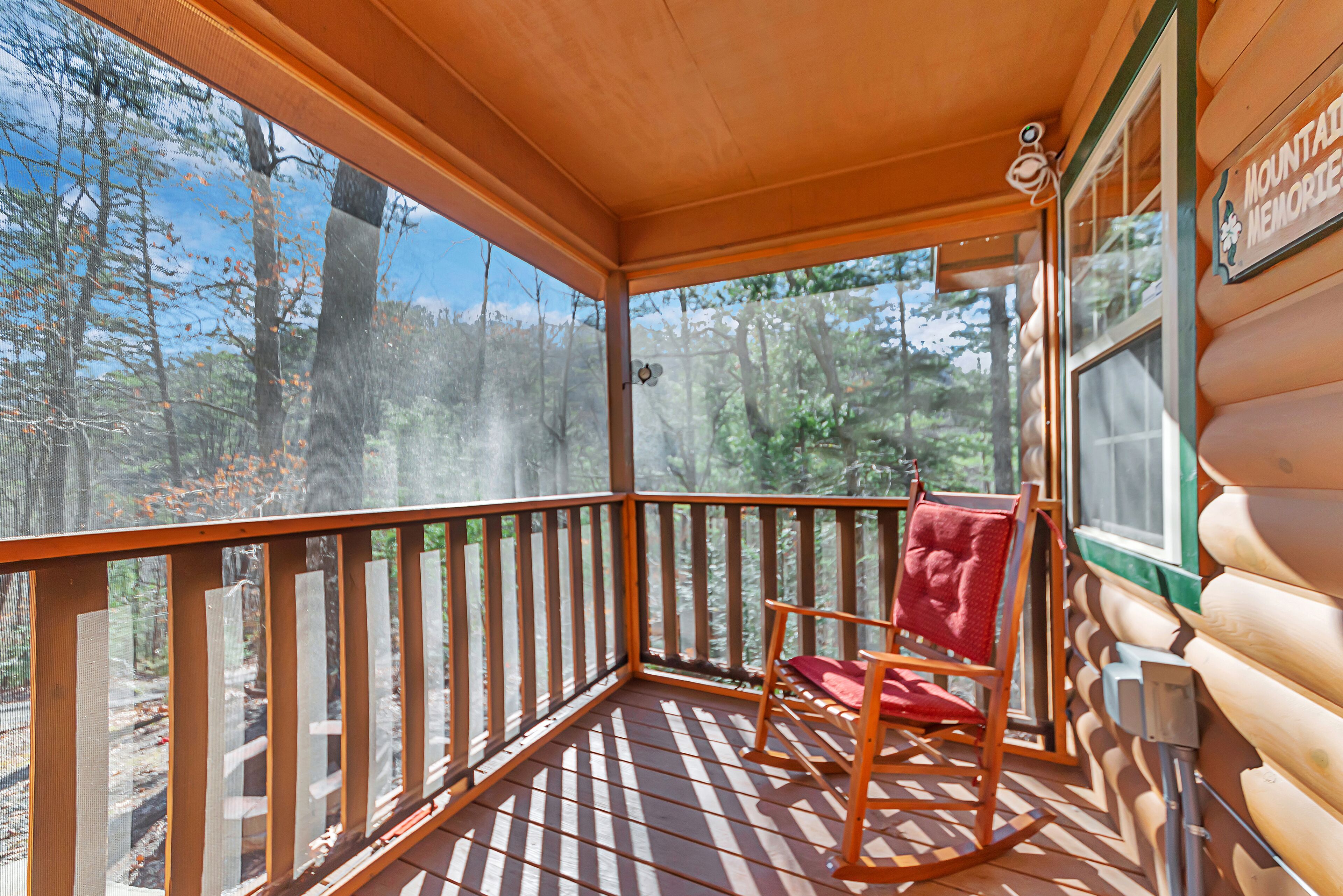 A wooden deck with a rocking chair and a window overlooking a forest.