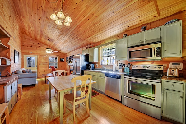 Interior de una cabaña de madera con comedor, cocina y una zona de estar acogedora.