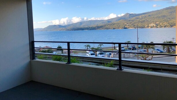 A balcony with a view of a body of water, mountains, and parked cars. - Standing apartment seen on sea (Propriano)