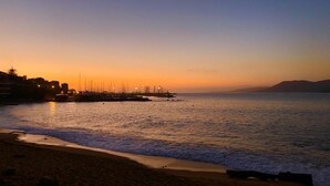 A beach at sunset with calm waters, a pier with boats, and distant mountains. - Standing apartment seen on sea (Propriano)