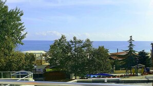 A coastal view with a beach area, trees, and buildings in the background. - 1-st Line Izvora Hotel Golden Sands (Golden Sands)