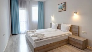 A modern bedroom with a wooden bed, a nightstand, and a painting on the wall. - 1-st Line Izvora Hotel Golden Sands (Golden Sands)