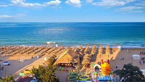 A beach with rows of sun loungers and a water park. - 1-st Line Izvora Hotel Golden Sands (Golden Sands)