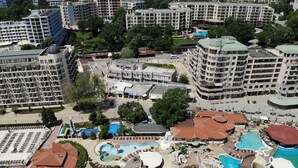 An aerial view of a resort with multiple buildings, a large swimming pool area, and surrounding greenery. - 1-st Line Izvora Hotel Golden Sands (Golden Sands)