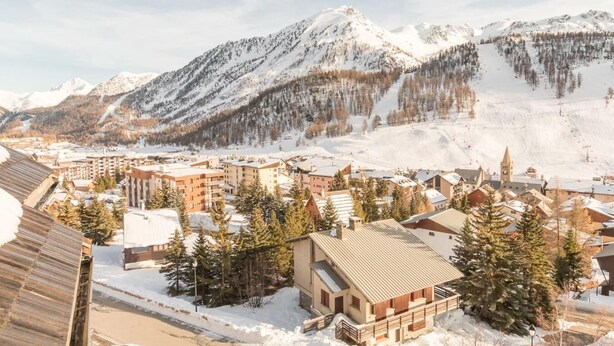 A snow-covered mountain town with buildings and a ski slope.