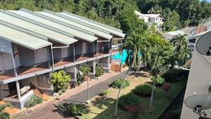 A multi-story building with balconies, a swimming pool, and surrounding greenery. - Cozy studio in Le Gosier 2 minutes from the beach (Le Gosier)