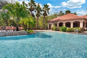 A swimming pool with a water feature, surrounded by palm trees and a building with a tiled roof. - TR6204TT - Upscale Renovated Condo with Resort Amenities (Davenport)