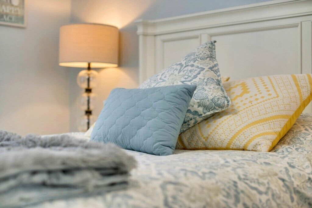 Un lit avec une literie à motifs, une lampe et un mur orné d’un tableau.