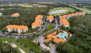 An aerial view of a resort with orange-roofed buildings, a swimming pool, and a golf course. - TR6204TT - Upscale Renovated Condo with Resort Amenities (Davenport)