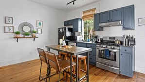 Una cocina moderna con una isla central, taburetes de bar y una estufa de acero inoxidable.
