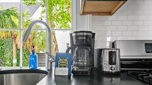 Una cocina con un lavamanos de acero inoxidable, una cafetera, un tostador y una botella de jabón para manos azul.