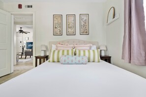 A bedroom with a bed, bedside tables, a ceiling fan, and a desk with a chair.