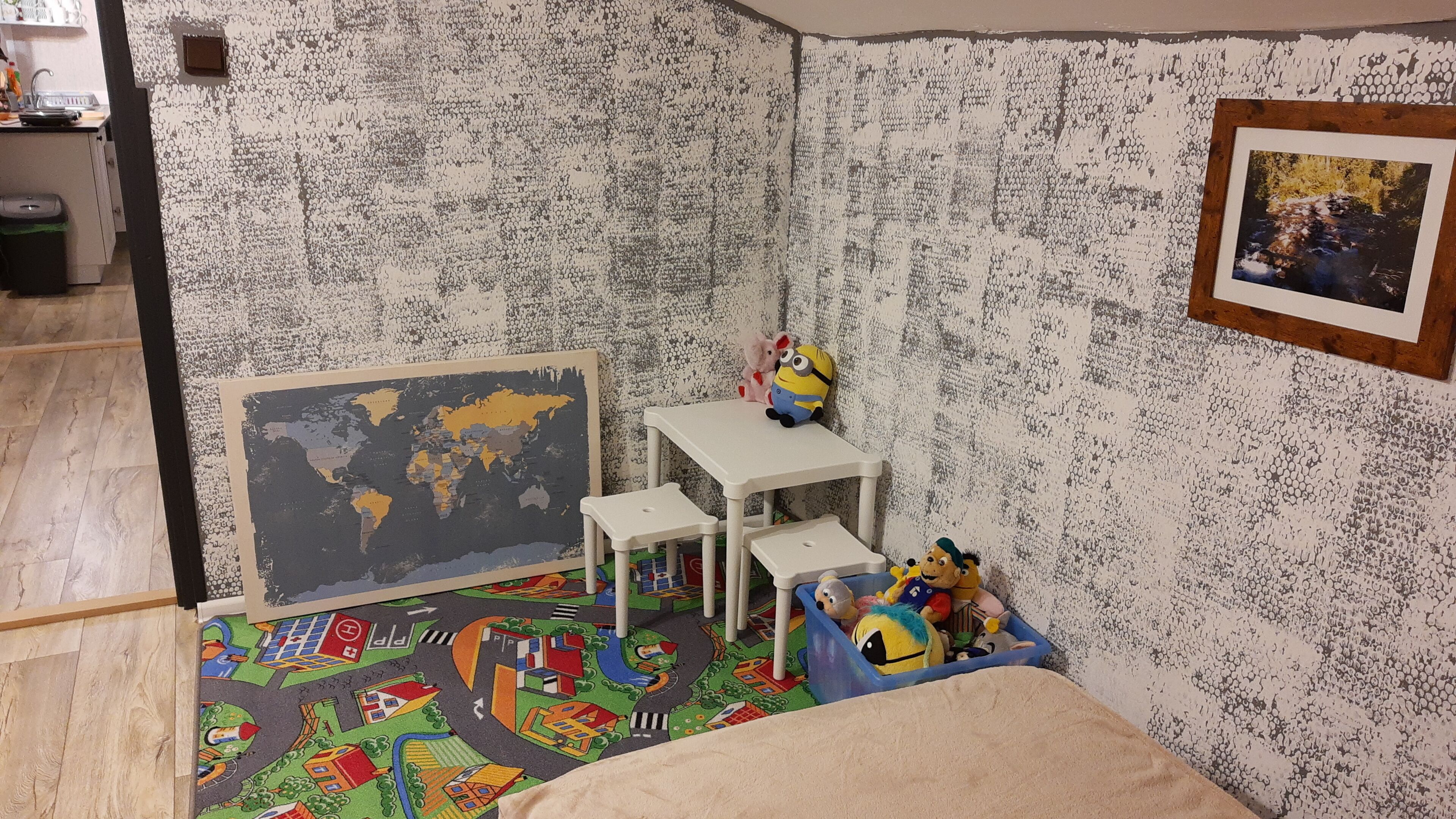 Een kinderkamer met een wereldkaart, een klein wit tafeltje en speelgoed.