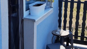 A balcony with a potted plant, a small table, and a chair. - Bluebell (Mengusovce)