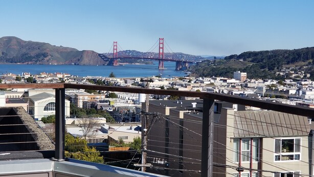 Een woonwijk met uitzicht op de Golden Gate Bridge, met huizen, een houten hek en boventracties.