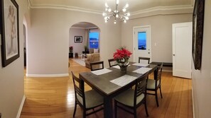 A dining area with a table set for four, a chandelier, and a view through an archway to another room. - Modern, Chic, 3bedroom/2bath, Patio, GGB/City views,snacks/instant breakfast. (SF)
