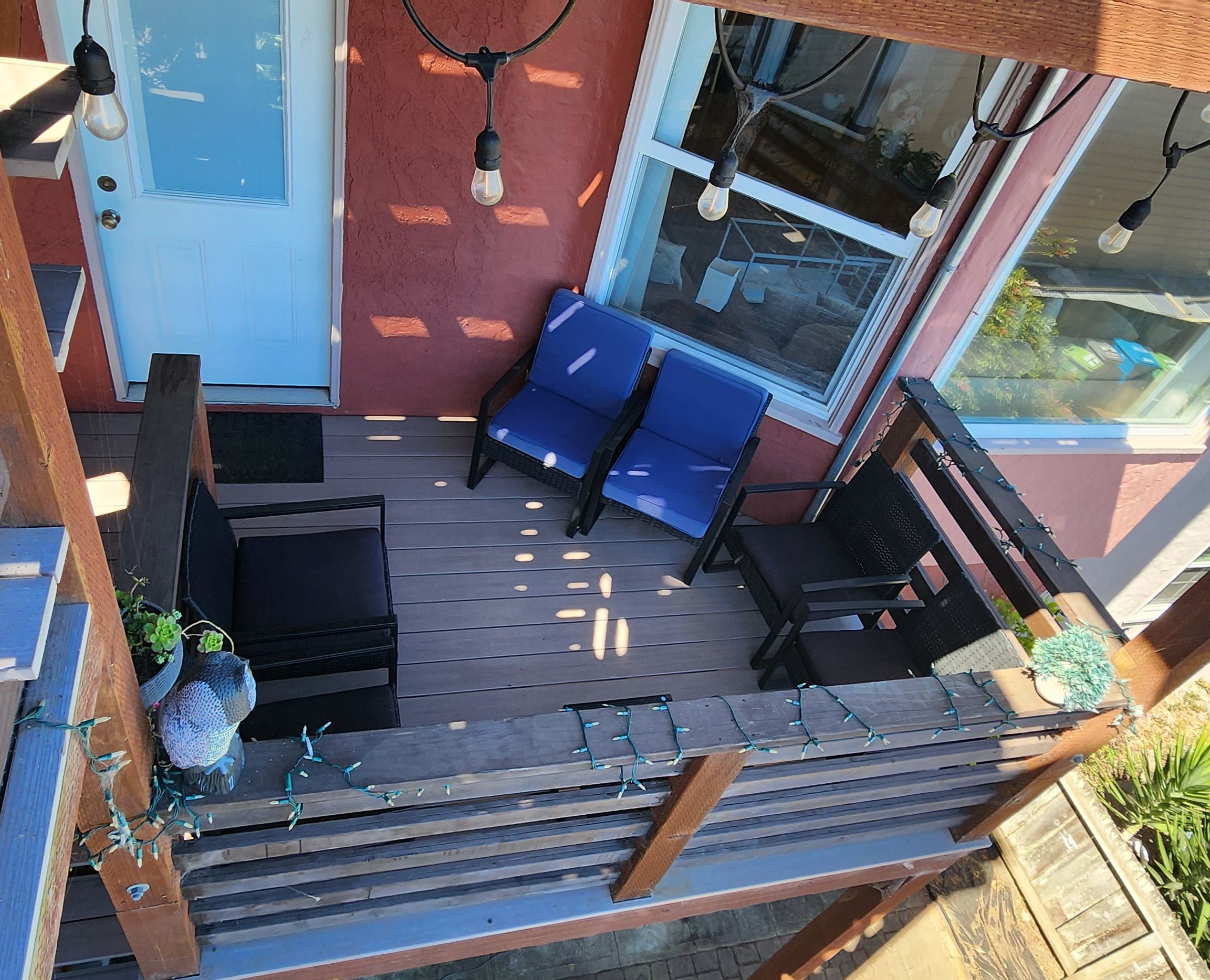 A covered outdoor seating area with a blue sofa, two chairs, and a small table.