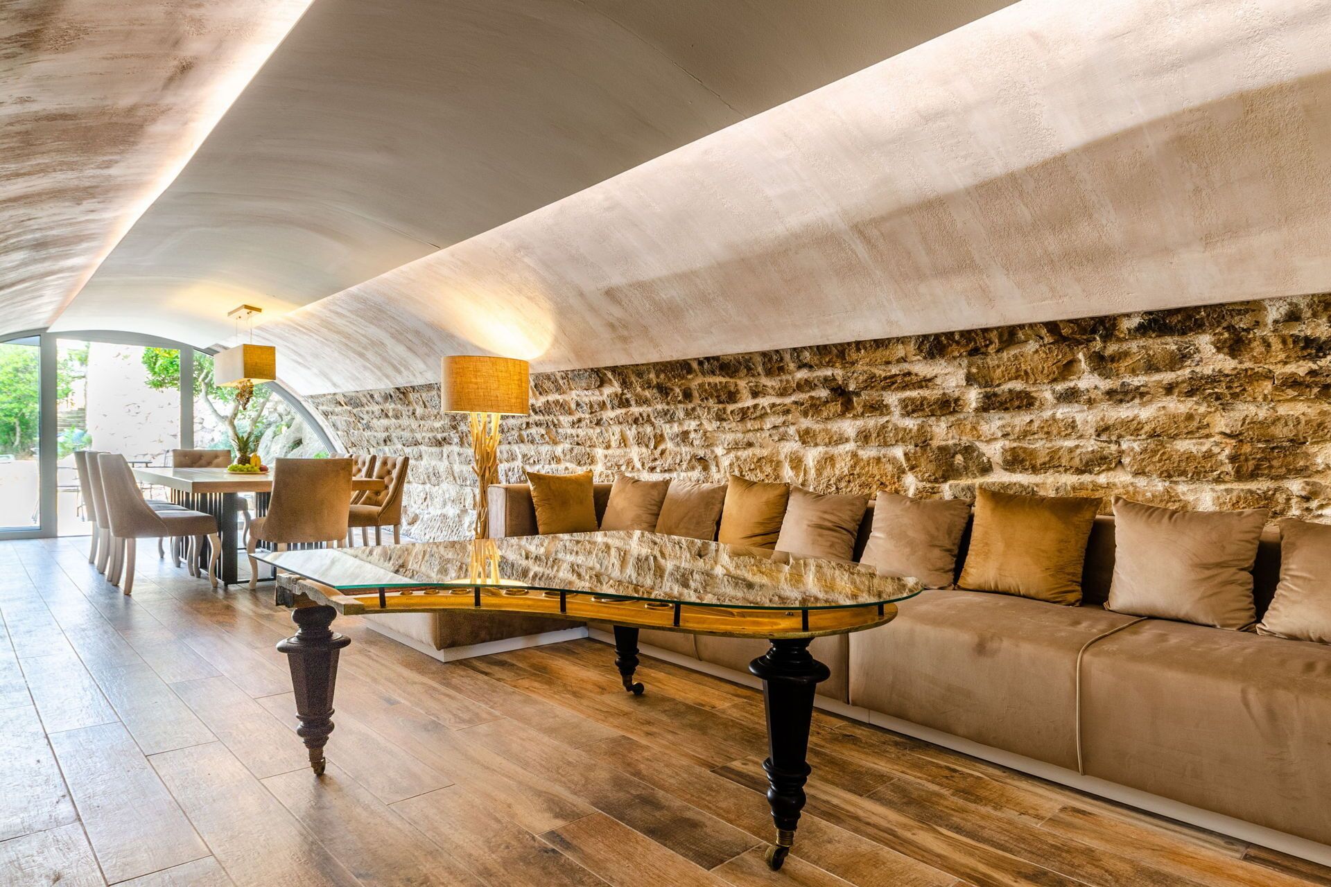 A modern interior with a stone wall, a sofa, and a dining table with chairs.