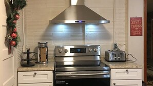 Cozinha com exaustor de aço inoxidável, forno embutido e torradeira na bancada.