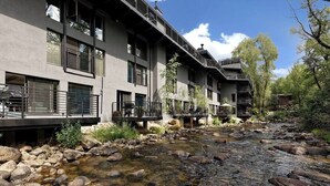 A multi-story hotel with balconies overlooking a rocky stream.