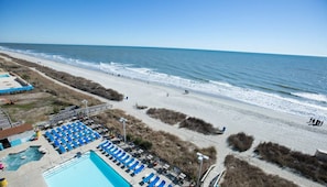 Blick auf einen Strand mit Poolbereich, einschließlich Liegestühlen und einem Schwimmbecken.