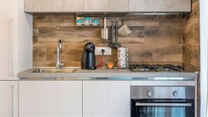 Une cuisine moderne équipée d’un évier en acier inoxydable, d’une machine à café, d’une cuisinière à gaz et d’un four encastré.