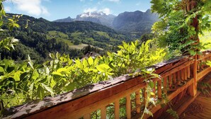 Un balcon en bois offrant une vue sur un paysage montagneux.