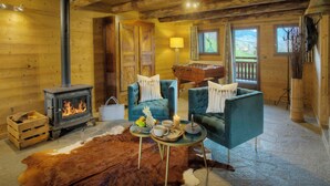 L’intérieur chaleureux d’un chalet en bois, avec un poêle à bois, des sièges confortables et une vue sur l’extérieur.