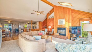 A spacious living room with a large sofa, a television, and a fireplace.