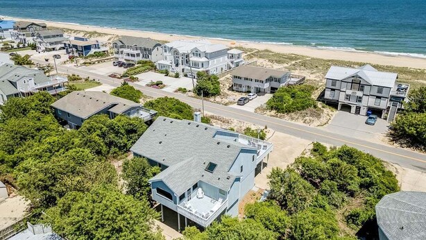 A coastal residential area with houses, a beach, and a road.