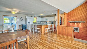 A spacious kitchen with wooden flooring, white cabinets, and a central island with bar stools.