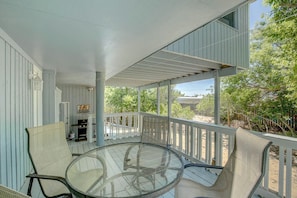 Relax in this serene outdoor space with a glass-top table and two wicker chairs, offering a tranquil view of the beach and lush surroundings.