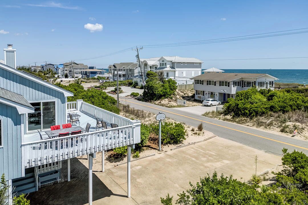 Un quartier résidentiel situé sur la côte, avec une maison dotée d’un balcon et de mobilier d’extérieur.