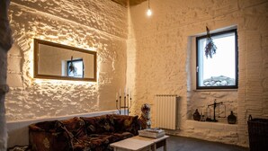 Una habitación acogedora con un sofá estampado, una mesita, un espejo y una ventana con vistas.