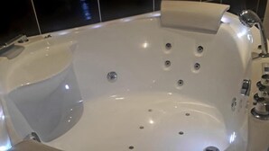 A modern, oval-shaped hot tub with multiple jets, a control panel, and a small vase with flowers on the edge. - Hôtel Renaissance Martigues (Martigues)