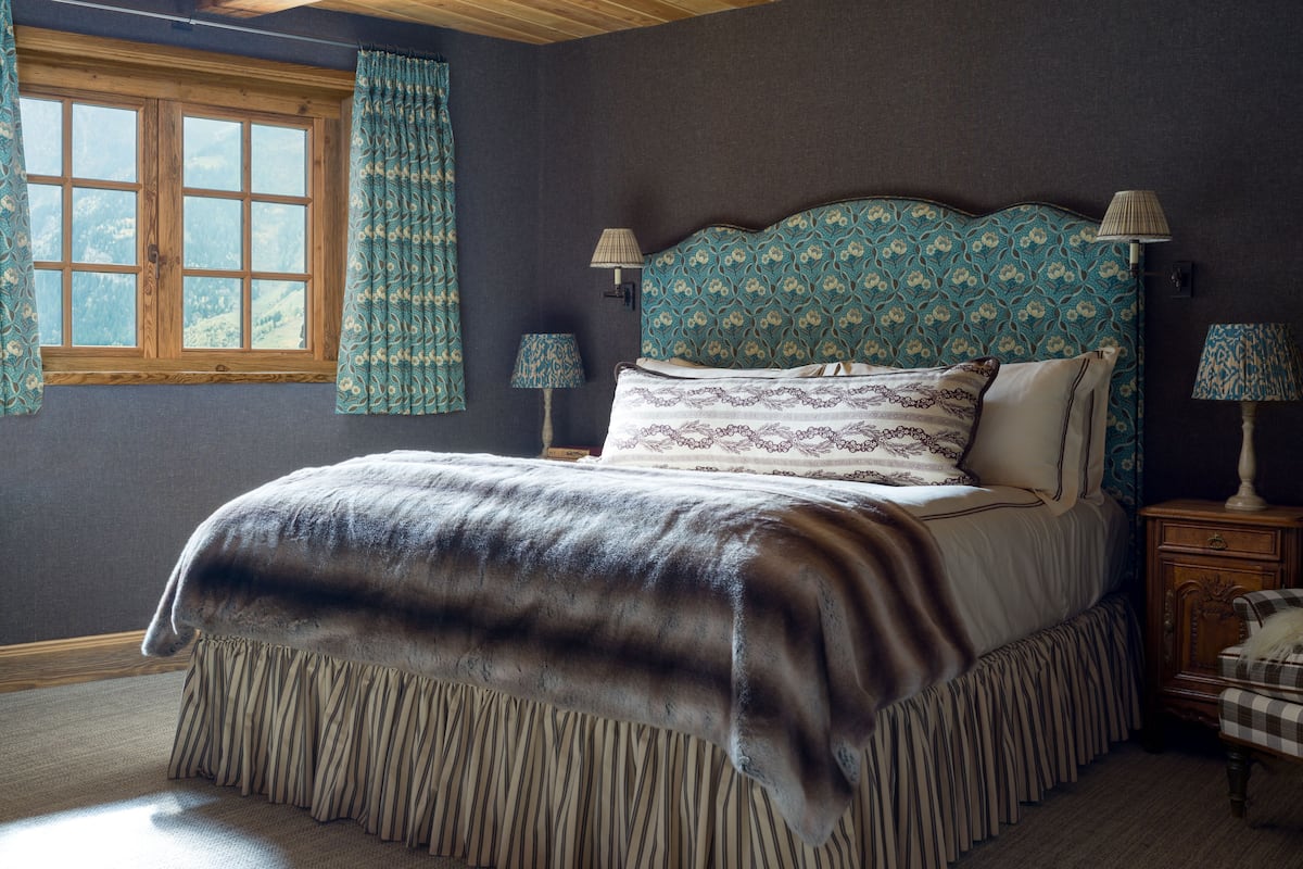 Un dormitorio con una cama grande, dos lámparas de noche, un ventanal con cortinas y vistas al exterior.